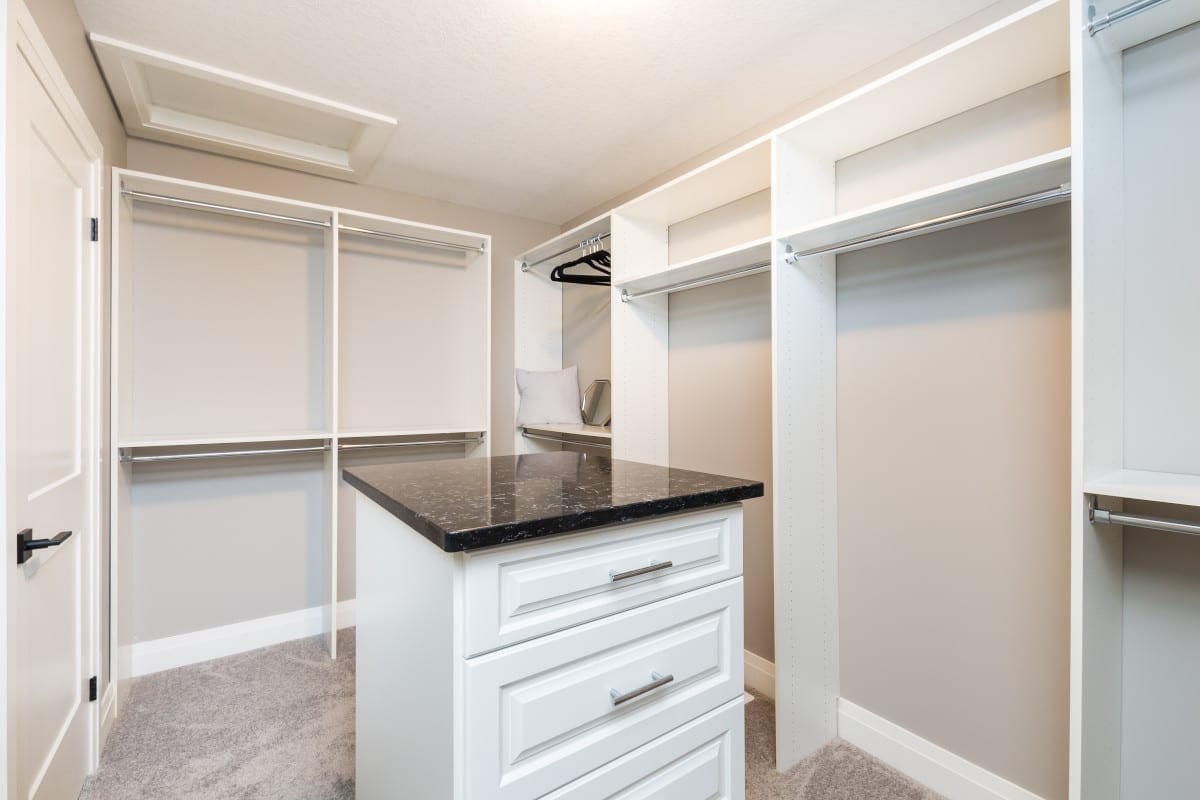 Large and spacious walk in closet featuring a central island with quartz countertop.