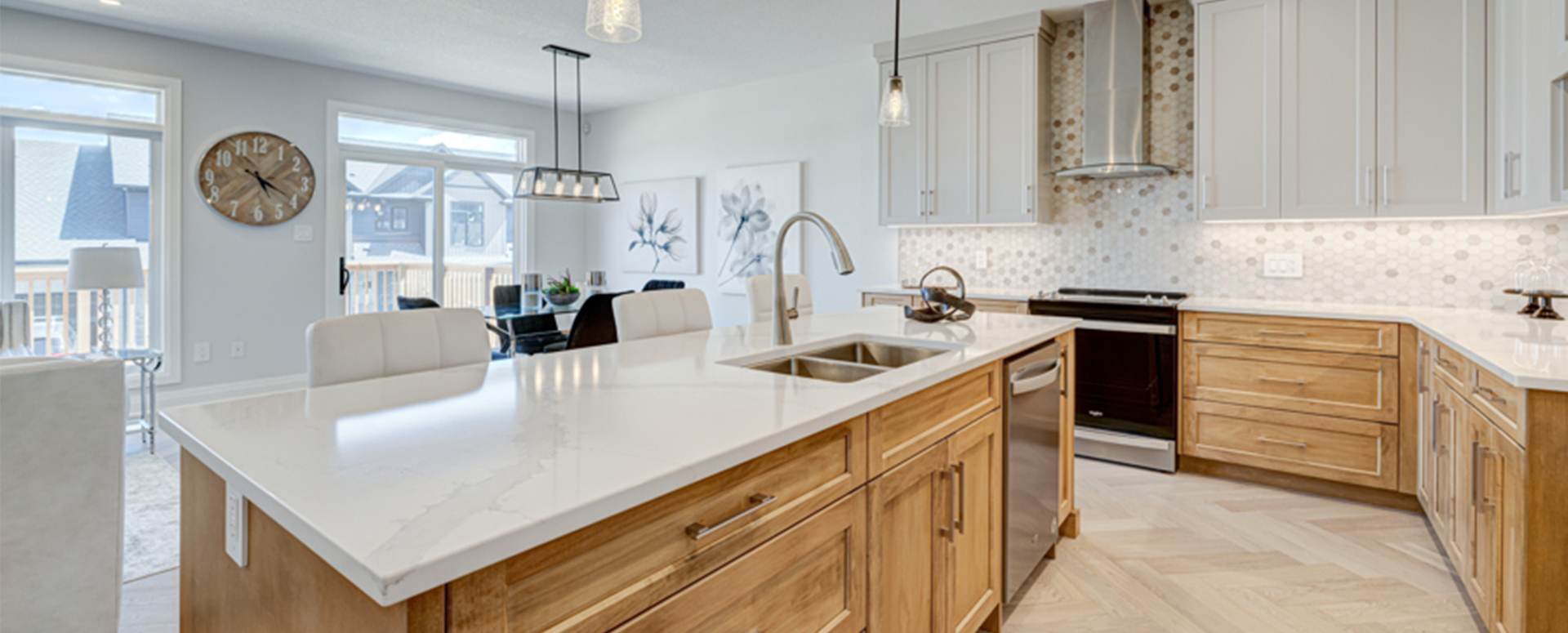 Warmly lit kitchen finished in soft white and wood cabinetry. Located at Upper West by Rembrandt Homes.